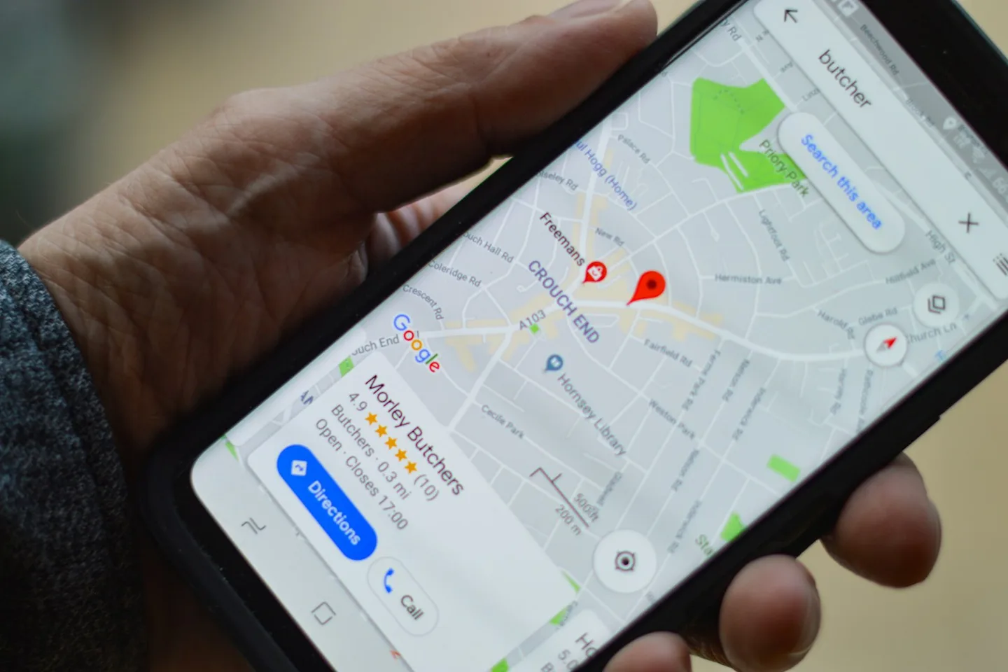 Hand holding a phone showing a local business result on a map